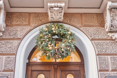 Christmas morning. House with a decorated door with a Christmas wreath and tree branches. Street european city