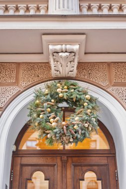 Christmas morning. House with a decorated door with a Christmas wreath and tree branches. Street european city