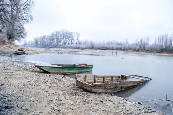 ドナウ川の支流の岸に係留されている木製の漁船が凍った水で係留されている — ストック写真