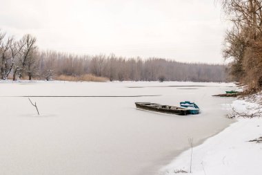 Tuna Nehri 'nin kıyısında donmuş suda demirli ahşap bir balıkçı teknesi..