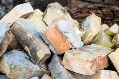 Arsanın yanındaki eski duvarda çizikler ve çatlaklar olan bir yığın kullanılmış tuğla..