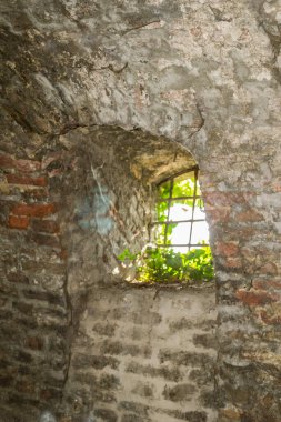 Petrovaradin Kalesi 'nin duvarında metal parmaklıklar olan eski pencere..