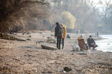 Novi Sad, Sırbistan. Mart - 16. 2022 yılı. Bahar güneşli bir günde, Tuna kıyılarında yürüyen insanlar..