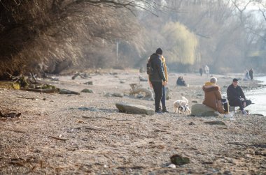 Novi Sad, Sırbistan. Mart - 16. 2022 yılı. Bahar güneşli bir günde, Tuna kıyılarında yürüyen insanlar..