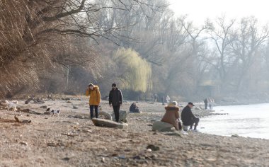 Novi Sad, Sırbistan. Mart - 16. 2022 yılı. Bahar güneşli bir günde, Tuna kıyılarında yürüyen insanlar..