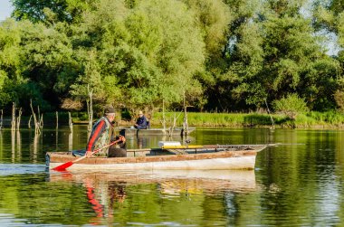 Novi Sad, Sırbistan - 17 Ağustos. 2019: Balıkçılar tahta tekneleriyle sahilin diğer tarafına geçiyor.