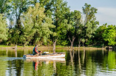 Novi Sad, Sırbistan - 17 Ağustos. 2019: Balıkçılar tahta tekneleriyle sahilin diğer tarafına geçiyor.