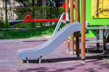 Güneşli bir bahar günü erken saatlerde oynanacak slayt ve oyunlar da dahil olmak üzere çeşitli oyuncakları olan renkli oyun alanı ekipmanları..
