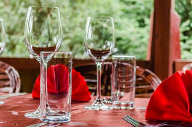 A dining table has been set up in the restaurant with red napkins as decoration and glass cups.