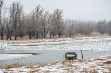 Tuna Nehri 'nin kıyısında donmuş suda demirli ahşap bir balıkçı teknesi..
