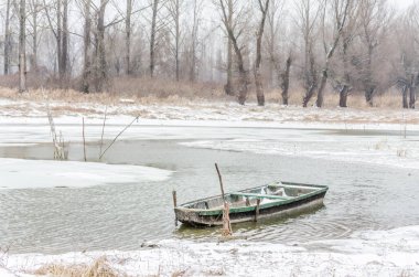 Tuna Nehri 'nin kıyısında donmuş suda demirli ahşap bir balıkçı teknesi..