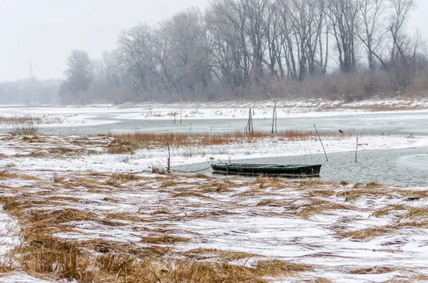 Tuna Nehri 'nin kıyısında donmuş suda demirli ahşap bir balıkçı teknesi..
