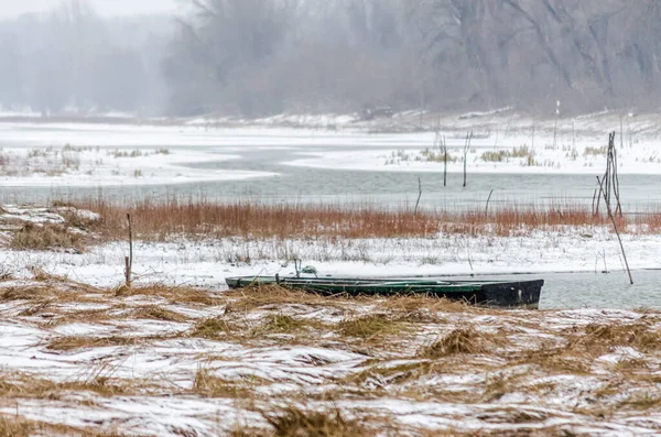 Tuna Nehri 'nin kıyısında donmuş suda demirli ahşap bir balıkçı teknesi..
