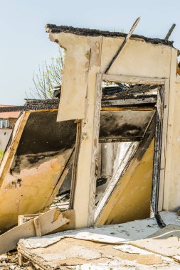 The remains of the burnt house. Ruined and collapsed house burnt and damaged in the fire with remains of the wooden reinforcement poles of roof selective focus. Burned house