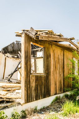 The remains of the burnt house. Ruined and collapsed house burnt and damaged in the fire with remains of the wooden reinforcement poles of roof selective focus. Burned house