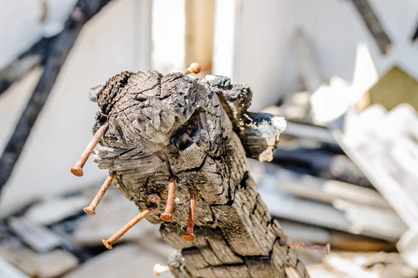 The remains of the burnt house. Ruined and collapsed house burnt and damaged in the fire with remains of the wooden reinforcement poles of roof selective focus. Burned house