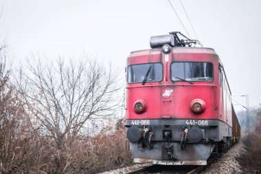 A view of the railway line in winter. An old electric locomotive on a railway track covered in daytime winter fog. The concept of traveling by train.