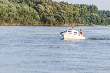 Novi Sad, Serbia - September 29. 2019: A panoramic view of the bank of the Danube river. A view of a small white boat with a cabin and passengers in the water.
