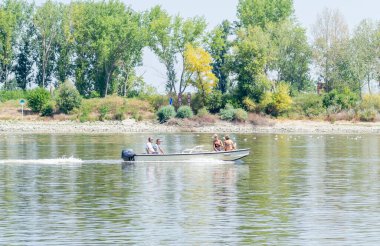 Novi Sad, Serbia - September 29. 2019: A panoramic view of the bank of the Danube river. A view of a small white boat with a cabin and passengers in the water.