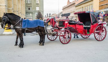 Novi Sad, Serbia - December 13. 2019: Downtown Novi Sad. Two horses harnessed in red carriages