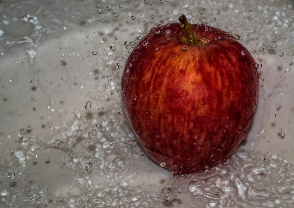 Apple covered in water. Apple covered with water in a metal bowl.