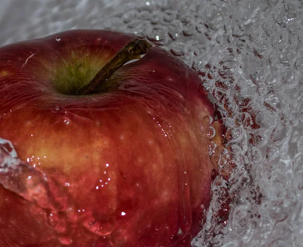 Apple covered in water. Apple covered with water in a metal bowl.