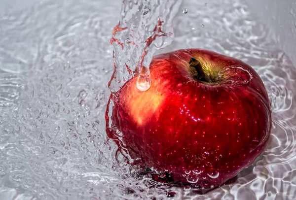 Apple covered in water. Apple covered with water in a metal bowl.