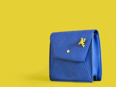 Sarı arka planda kurbağa olan küçük mavi kadın çantası.