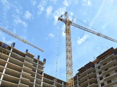 Construction of a new residential complex. High-rise crane on a background of blue sky.