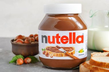 KREMENCHUG, UKRAINE - 9 Ekim 2021: Nutella cam kavanozu mutfakta kahvaltıda taze pişmiş ekmek. Tatlı fındıklı çikolatalı krema. Ferrero 'nun dünyaca ünlü İtalyan markası.