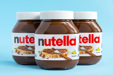 KREMENCHUG, UKRAINE - 9 Ekim 2021 Nutella. Mavi arka plana yayılmış üç kavanoz çikolata. Fındıklı kakao ezmesinin popüler markası.