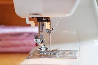 Dikiş makinesinin iğne ve baskılı ayağına yakın çekim, seçici odaklanma.