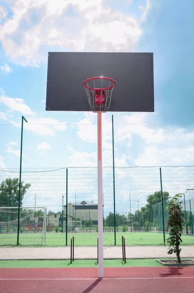 Basketball backboard with a basket made of iron chains on a sunny day. Vertical view. Low angle view