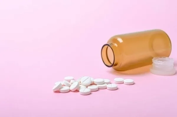 白色圆形药丸分散在粉色背景的棕色瓶子上 药学和保健主题 医疗背景 复制空间 — 图库照片