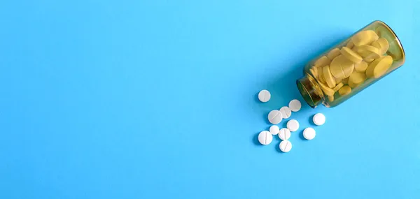 白色圆形药丸分散在蓝色背景的棕色瓶子上 药学和保健主题 医疗背景 复制空间 成瘾治疗 社会健康问题概念 — 图库照片