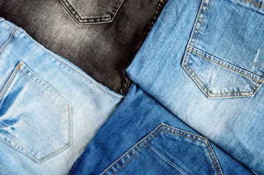 Çeşitli kot pantolonlardan arkaplan. Cepleri olan pamuk pantolon ve turuncu dikişli dikiş, üst manzara..