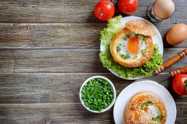 Ahşap bir arka planda yumurta ve pastırmayla doldurulmuş pişmiş çörekler. Lezzetli ve hızlı bir kahvaltı. Sağlıklı beslenme konsepti. Kopyalama alanı olan yiyecek arkaplanı.