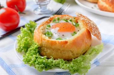 Ahşap bir arka planda yumurta ve pastırmayla doldurulmuş pişmiş çörekler. Lezzetli ve hızlı bir kahvaltı. Sağlıklı yeme kavramı.