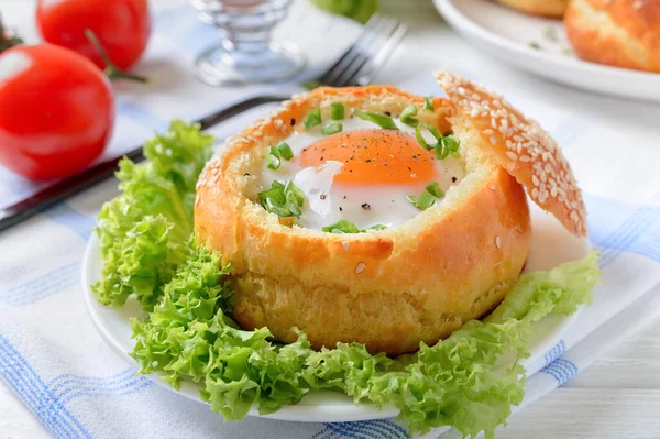 Ahşap bir arka planda yumurta ve pastırmayla doldurulmuş pişmiş çörekler. Lezzetli ve hızlı bir kahvaltı. Sağlıklı yeme kavramı.