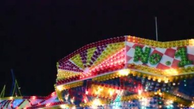 Geceleyin lunaparkta parlak renkli ışıkları olan bir gece atlıkarıncası..