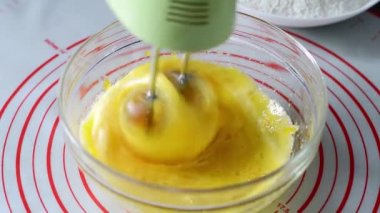 Kadın ev yapımı omlet hazırlıyor. Şeffaf bir kasede yumurta çırpıyor. Yakın plan.