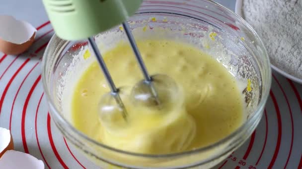 搅拌机混合配料 在用电动搅拌机在透明的碗里烘焙之前 女手先打蛋 然后把搅拌机放在桌上 — 图库视频影像