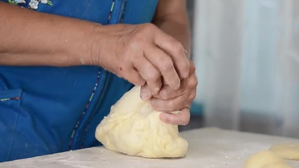 青のドレスを生の生地をつまんでパンを形成する高齢者の女性の手のクローズアップ 料理の伝統 家庭料理 — ストック動画