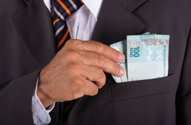 İş adamı Brezilya parasını takım elbisesinin cebinde tutuyor..