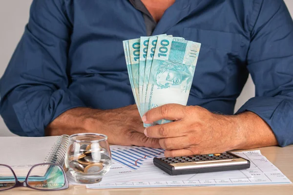 Brezilya parası işte. Elinde 100 banknot tutan bir iş adamı. finans ve iş kavramı.
