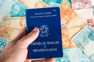 Brezilya para banknotları ile el ele tutuşan Brezilya belge işleri ve sosyal güvenlik (Carteira de Trabalho e Previdencia Social).