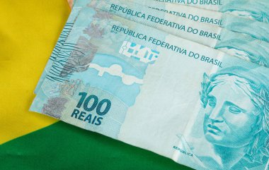 Brezilya para banknotları ve arka planda Brezilya bayrağı.