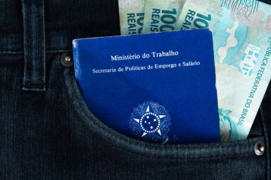 Kotunun cebinde yüz reais banknotla Brezilya 'ya ait belge işleri ve sosyal güvenlik işleri (Carteira de Trabalho e Previdencia Social) bulunmaktadır. Brezilya parası..