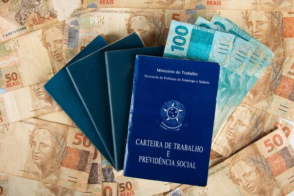 Brazilian document work and social security (Carteira de Trabalho e Previdencia Social) with Brazilian money banknotes.