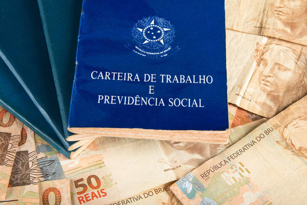 Brazilian document work and social security (Carteira de Trabalho e Previdencia Social) with Brazilian money banknotes.